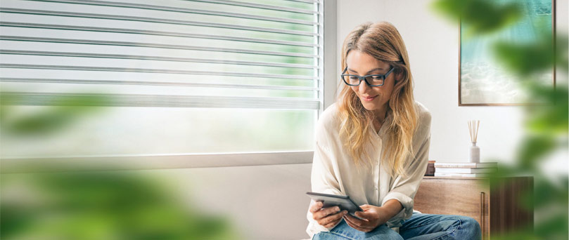 Young businesswoman with eyeglasses reading something on digital tablet in the living room